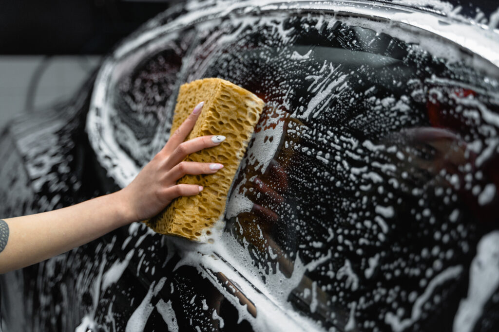 Photo of a person cleaning the window of a black car